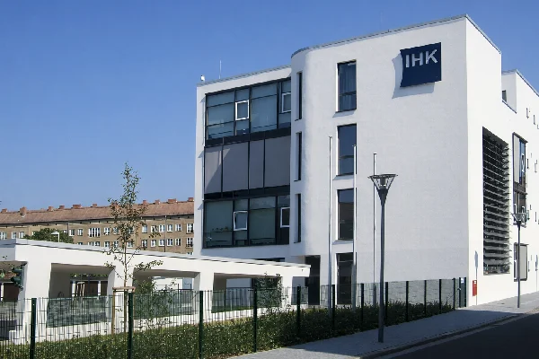 Gebäude der IHK Halle-Dessau Geschäftsstelle Dessau, moderner weißer Neubau mit IHK-Schild, blauer Himmel